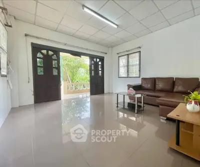 Spacious living room with large windows and modern brown sofa, offering a bright and airy atmosphere.