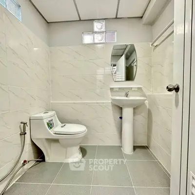 Modern bathroom with sleek design and elegant fixtures, featuring a pedestal sink and tiled walls.