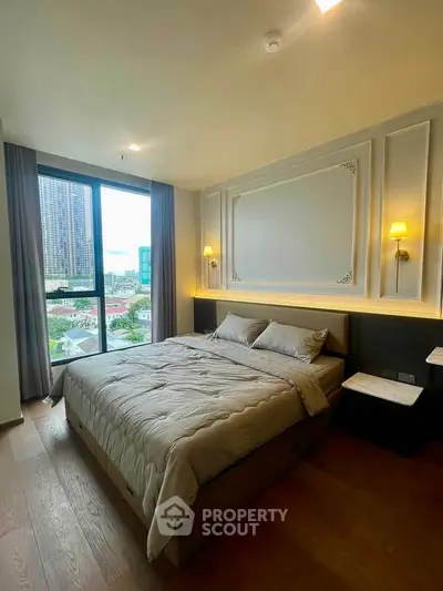 Modern bedroom with large window and city view, featuring elegant wall paneling and cozy bedding.