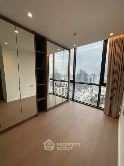 Spacious modern bedroom with floor-to-ceiling windows offering stunning city views.