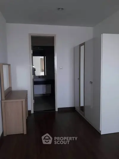 Spacious bedroom with modern wardrobe and vanity, featuring sleek wooden flooring.