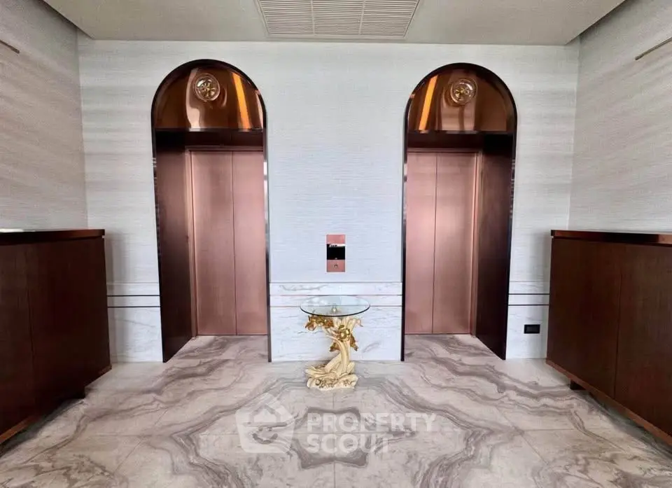 Luxurious marble-floored elevator lobby with elegant decor and dual elevators.