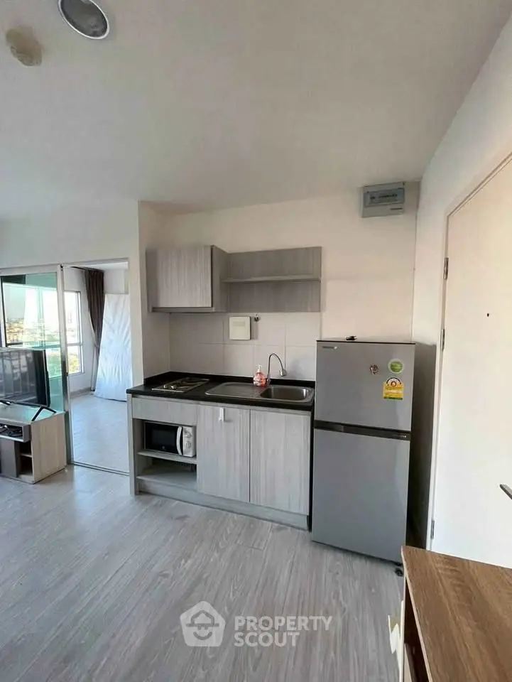 Modern kitchen with sleek cabinets and stainless steel appliances in open layout apartment.
