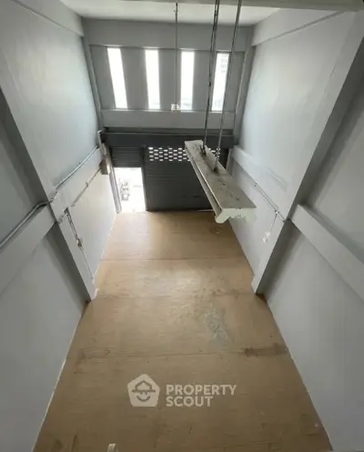 Spacious industrial-style unit with high ceilings and large windows, ideal for creative workspace or storage.