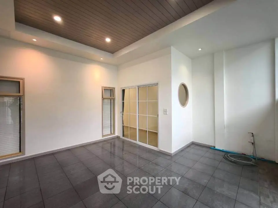 Spacious modern room with sleek tile flooring and recessed lighting, perfect for versatile living space.