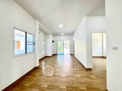 Spacious open-plan living area with wooden flooring and ample natural light.