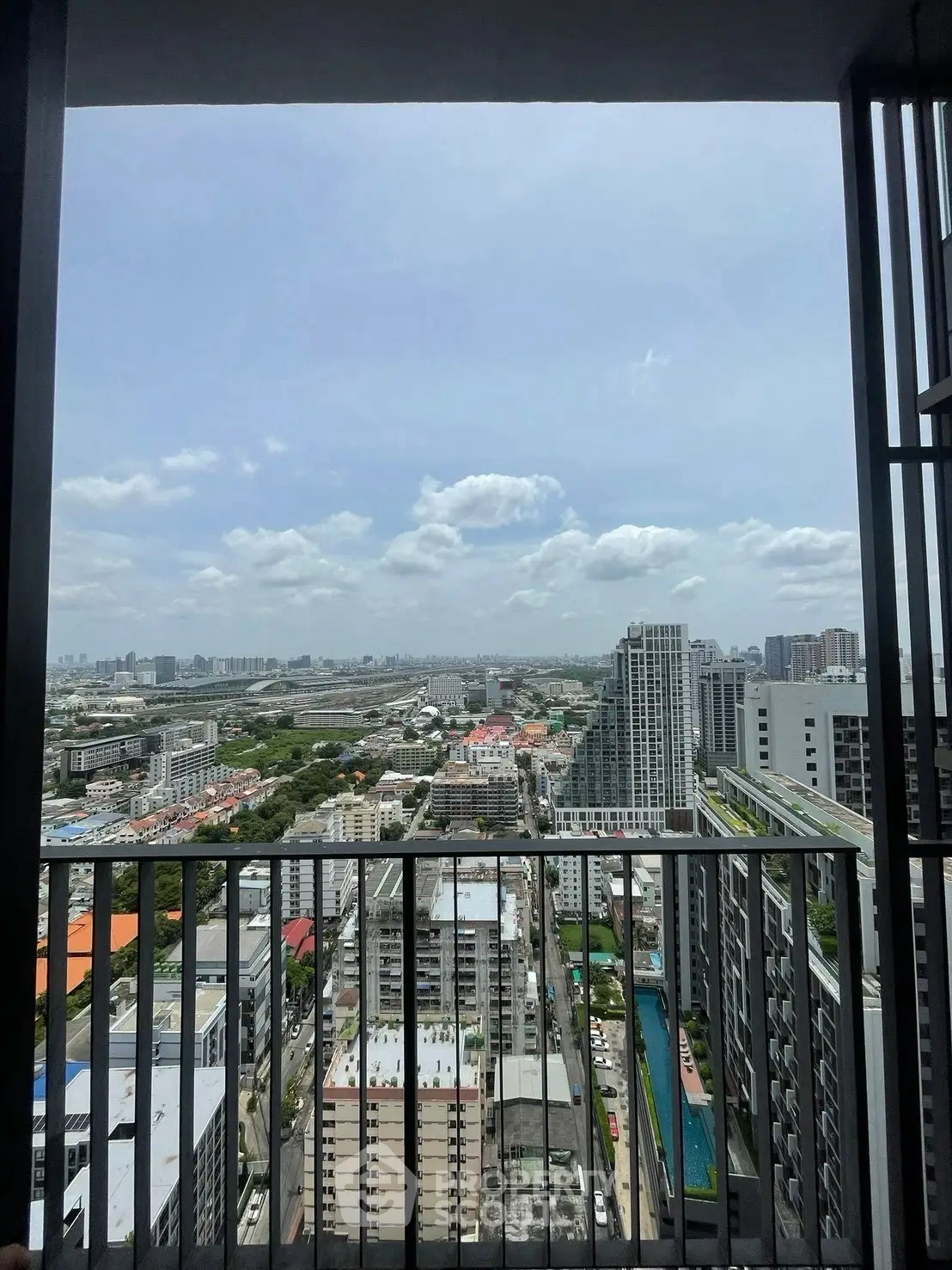 Stunning high-rise balcony view overlooking cityscape with modern buildings and clear skies.