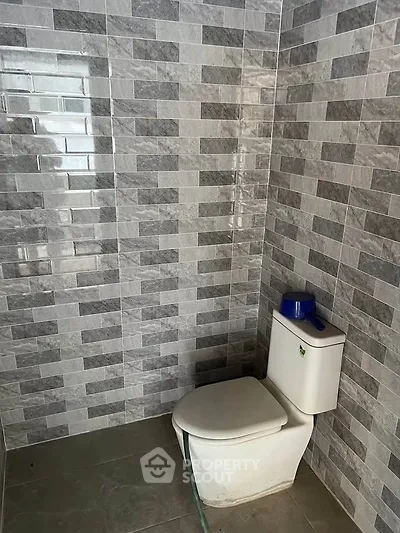 Modern bathroom with sleek tiled walls and contemporary toilet design.