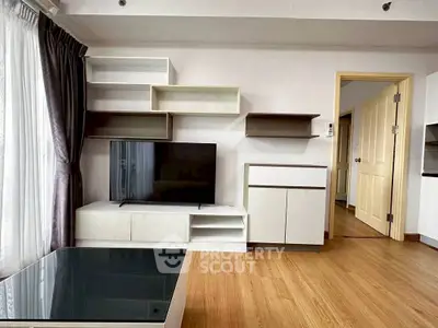 Modern living room with stylish shelves and TV, featuring wooden flooring and natural light.