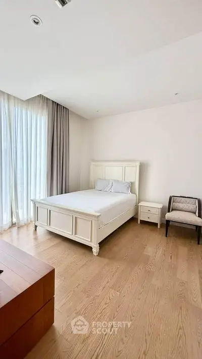 Spacious bedroom with elegant wooden flooring and large windows for natural light.