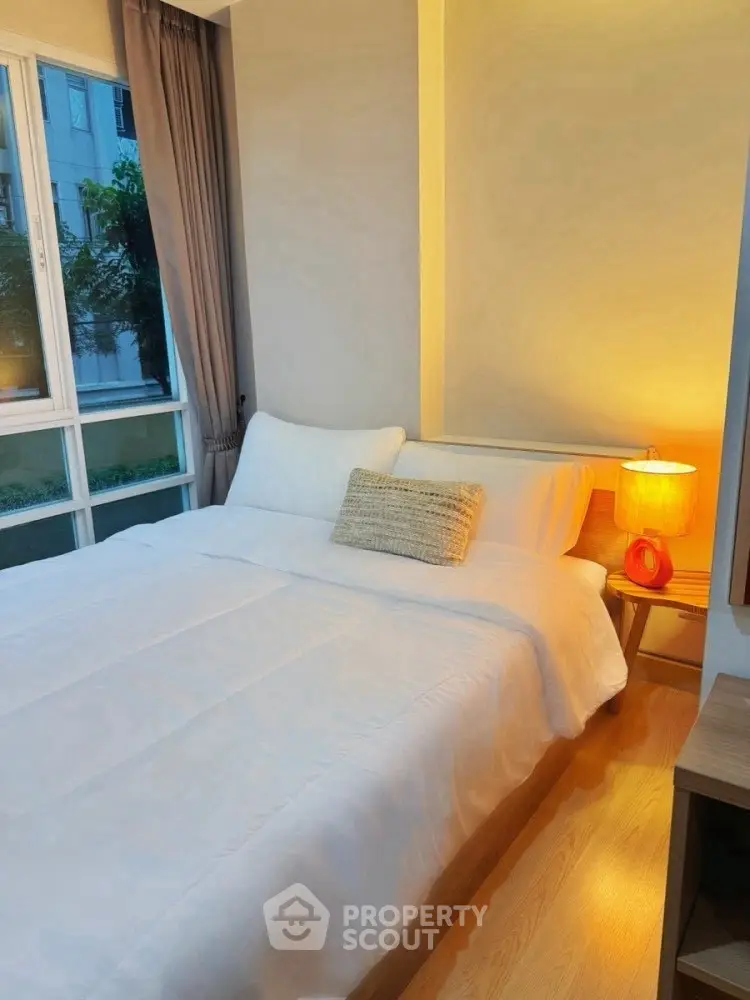 Cozy bedroom with large window and warm lighting in modern apartment.