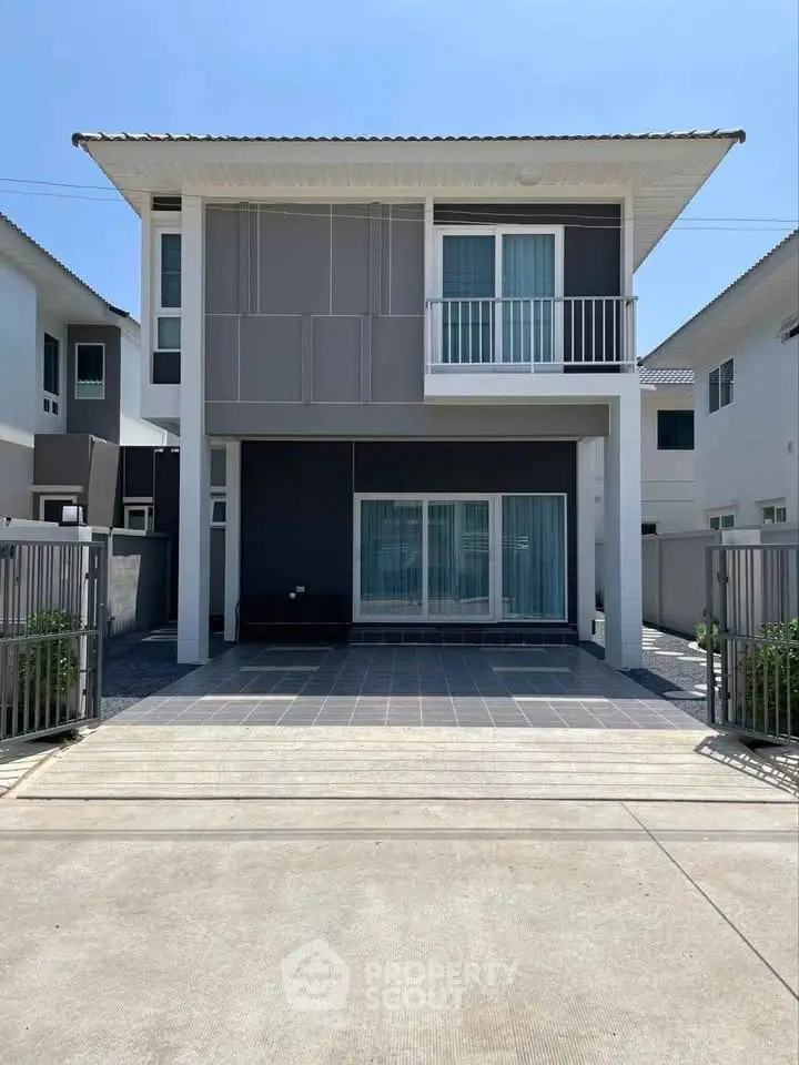 Modern two-story house with sleek design and spacious driveway in a suburban neighborhood.