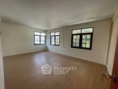 Spacious empty room with large windows and wooden flooring, ideal for customization.