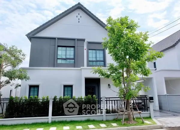 Modern two-story house with sleek design and lush greenery in a suburban neighborhood.