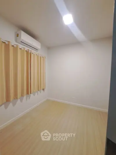 Spacious empty room with wooden flooring and air conditioning, perfect for customization.