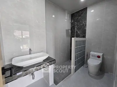 Modern bathroom with sleek design, featuring a stylish sink and a glass-enclosed shower area.
