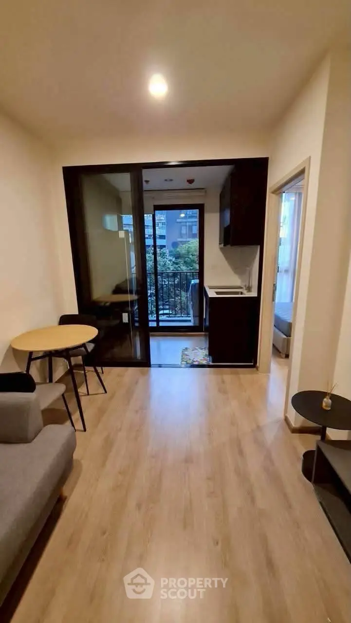 Modern apartment living room with balcony view and open kitchen layout.
