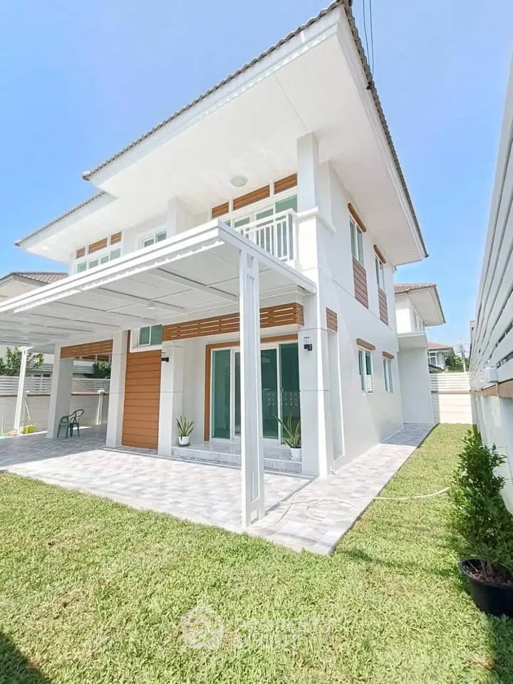 Modern two-story house with spacious patio and lush green lawn, perfect for family living.