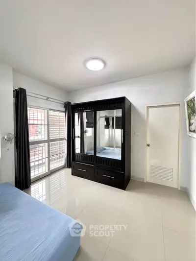 Spacious bedroom with large wardrobe and natural light from window.