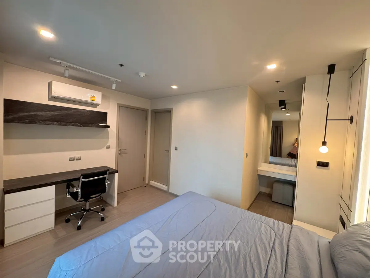 Modern bedroom with sleek design, featuring a comfortable bed, built-in desk, and stylish lighting.