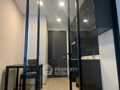 Modern compact kitchen with sleek black cabinets and glass partitions in a stylish apartment.