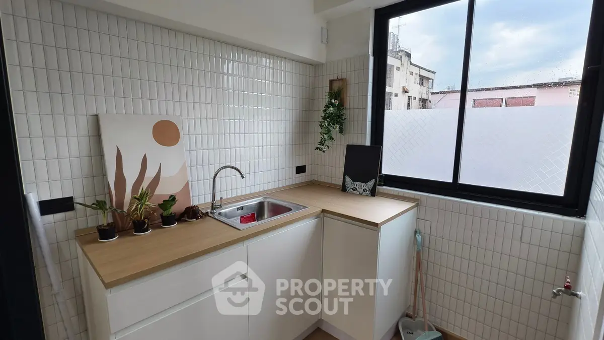 Modern kitchen with sleek design, featuring a corner sink and large window for natural light.
