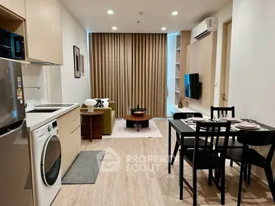 Modern open-layout living room with dining area and kitchen, featuring stylish furniture and appliances.