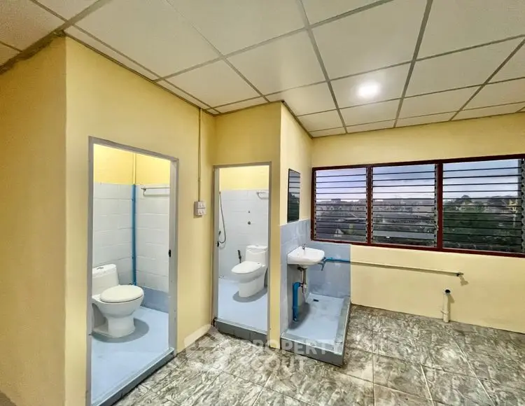 Spacious bathroom with separate toilet and shower areas, featuring large windows for natural light.