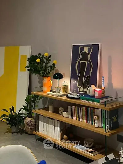 Stylish living room with modern decor and artistic elements, featuring a bookshelf and ambient lighting.
