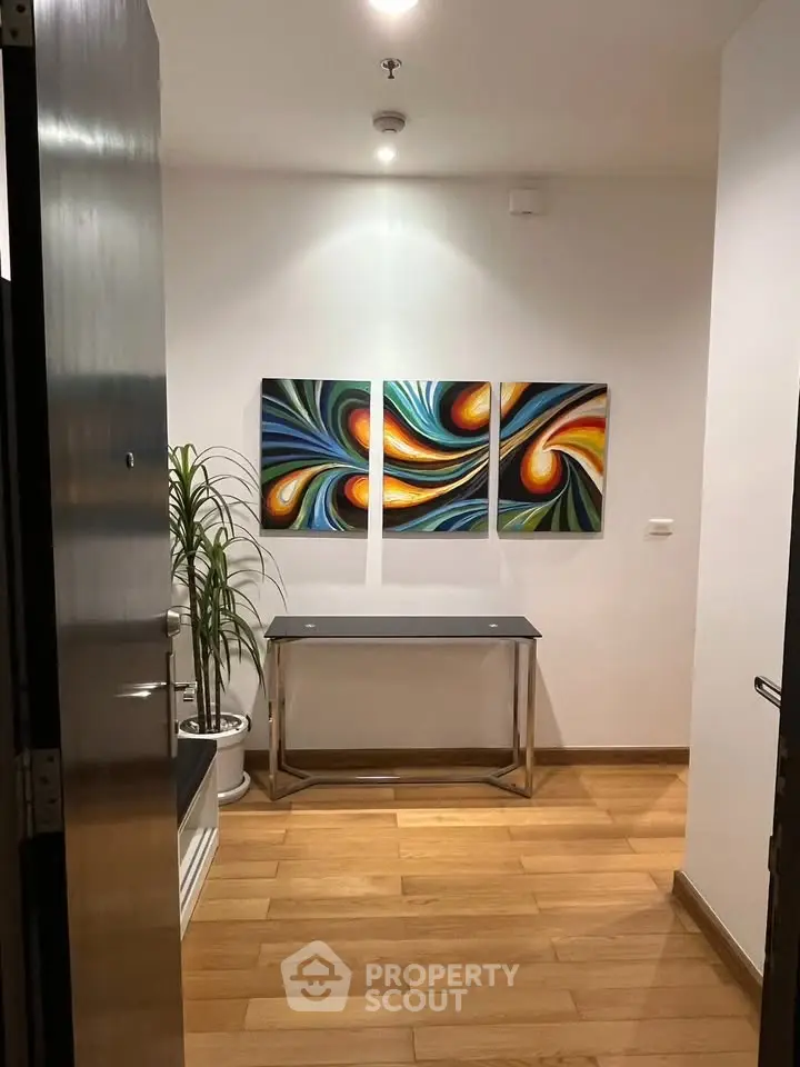 Stylish entryway with modern art and wooden flooring in a contemporary home.