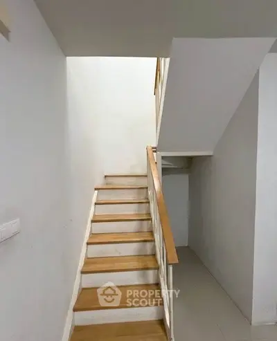 Modern staircase with wooden steps and white walls in a contemporary home.