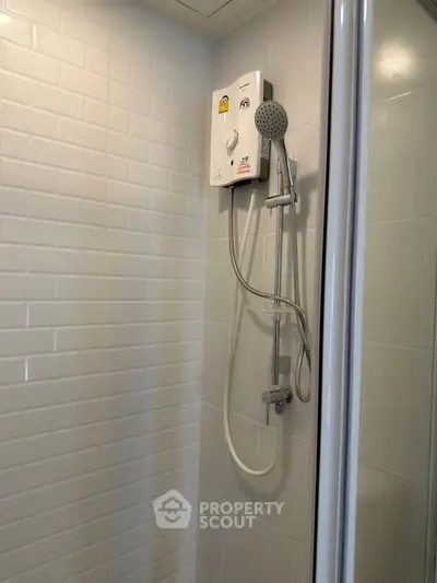Modern bathroom shower with sleek white tiles and water heater unit.