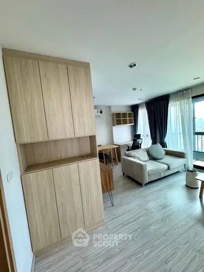 Modern living room with stylish furniture and large windows offering natural light and city views.