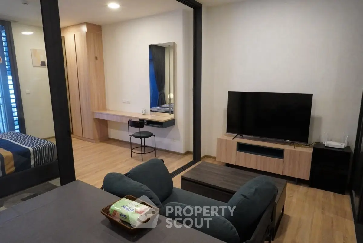 Modern living room with sleek furniture and TV, adjacent to a cozy bedroom, perfect for urban living.
