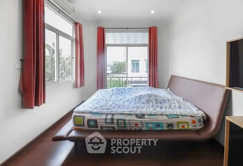 Modern bedroom with stylish bed and large windows offering natural light and garden view.