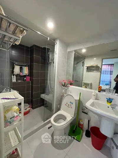 Modern bathroom with glass shower, toilet, and sink in a stylish apartment.