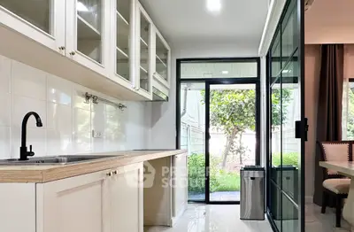 Modern kitchen with open layout and garden view, featuring sleek cabinetry and ample natural light.