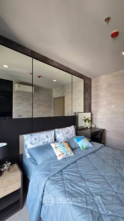 Modern bedroom with stylish decor and mirrored wall in a contemporary apartment.