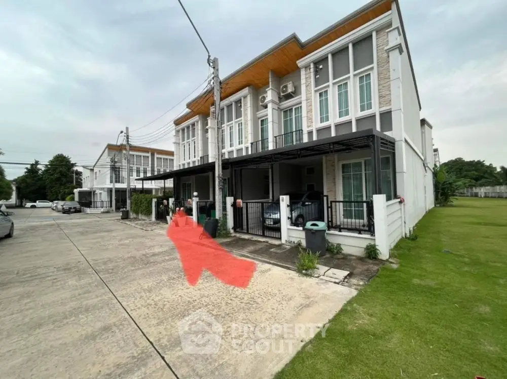 Modern townhouse with spacious driveway and green lawn in suburban neighborhood.