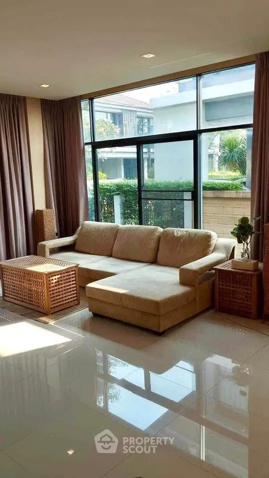 Spacious living room with large windows and modern beige sofa in a bright, elegant setting.