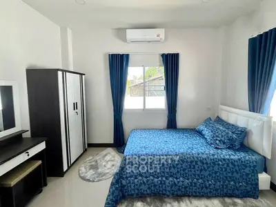 Modern bedroom with blue bedding, white walls, and air conditioning, featuring a sleek wardrobe and vanity.