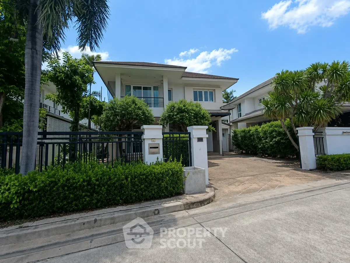 Luxurious modern house with lush greenery and spacious driveway in a serene neighborhood.