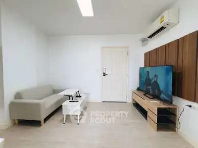 Modern living room with sleek furniture and wall-mounted TV, featuring a minimalist design and bright ambiance.
