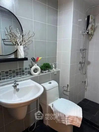 Modern bathroom with sleek fixtures and stylish decor, featuring a shower and elegant sink area.