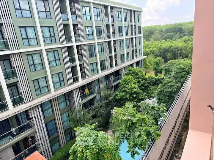 Modern apartment building with lush greenery and pool view, perfect for urban living.