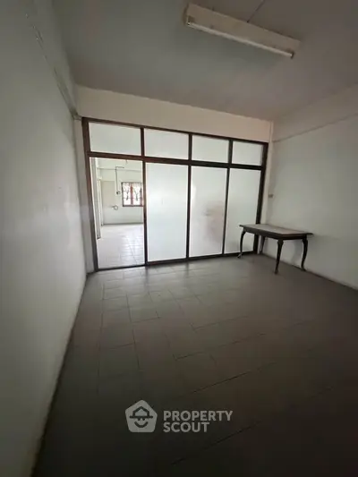 Spacious room with tiled flooring and glass partition, ideal for office or study setup.