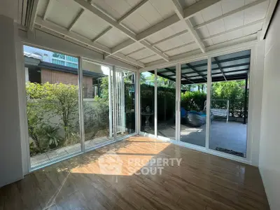 Spacious sunlit room with large glass doors opening to a lush garden view.