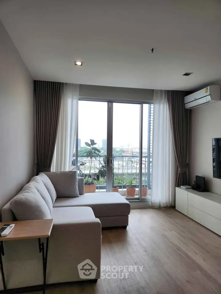 Modern living room with large windows and city view, featuring a cozy sofa and sleek decor.