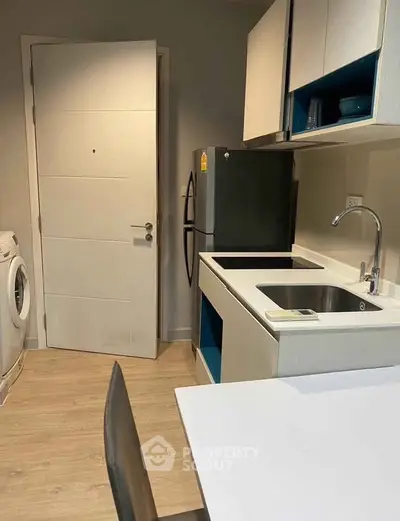 Modern kitchen with sleek appliances and washing machine in compact layout