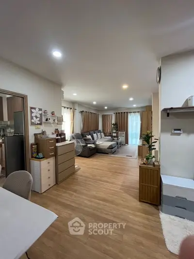 Spacious living room with modern decor and wooden flooring, perfect for family gatherings.